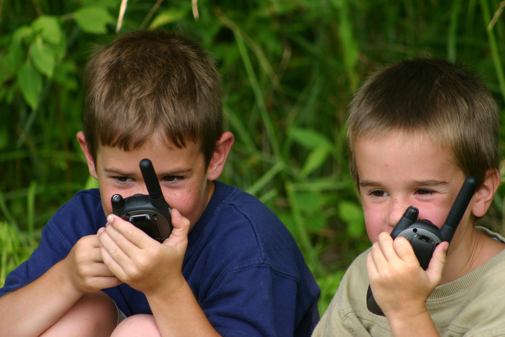 Photograph of two young boys playing outdoors with walkie-talkies